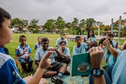 A group of students are reading a book together on the playground.